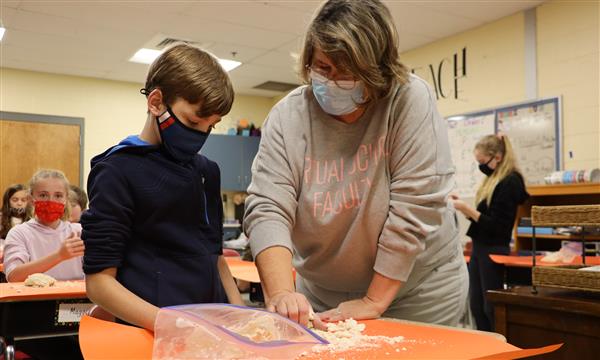 Teacher helps student with salt dough craft